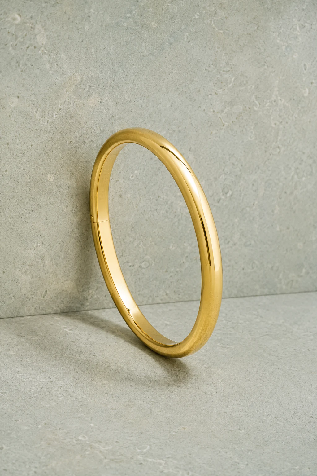 Classic polished gold bangle presented on cool limestone